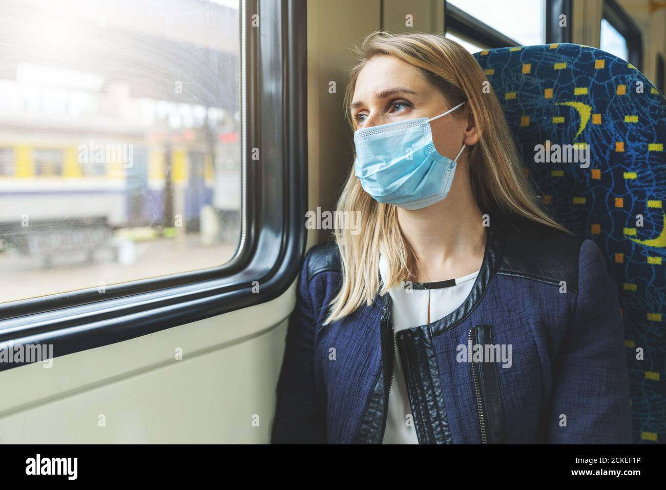 donna con maschera di sicurezza seduta in treno e guardando attraverso la finestra. virus pandemia Foto Stock
