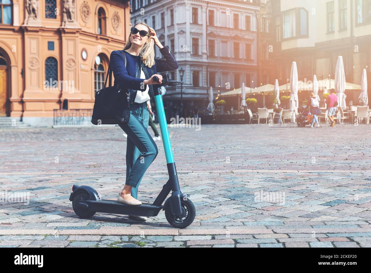 la donna millenaria guida uno scooter elettrico nelle strade della città. trasporto ecocompatibile Foto Stock
