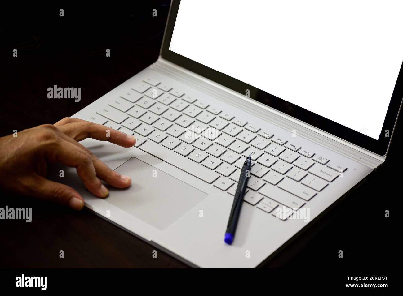 Primo piano di un uomo che scrive sulla tastiera del notebook contro il nero sfondo Foto Stock
