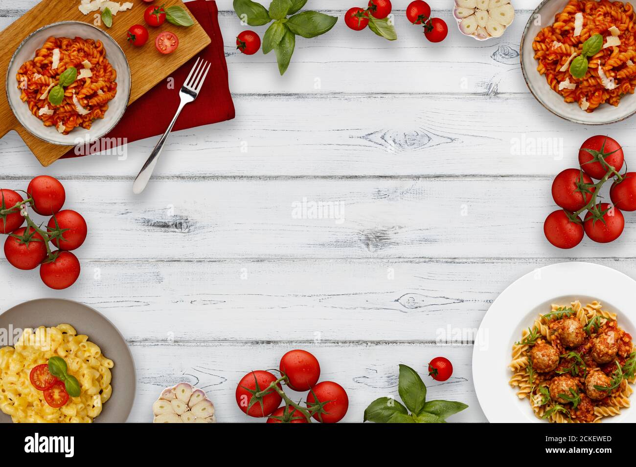 Un bordo di ciotole di deliziosa pasta a base di pomodoro, guarnite con erbe tradizionali, che mostrano anche ingredienti, su uno sfondo di legno bianco con spa Foto Stock