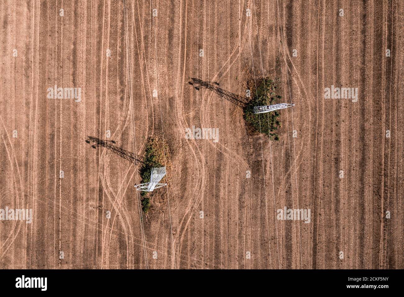 Vista aerea dei piloni elettrici nel campo agricolo che colano l'ombra sui raccolti, vista dall'alto, fotografia di droni Foto Stock