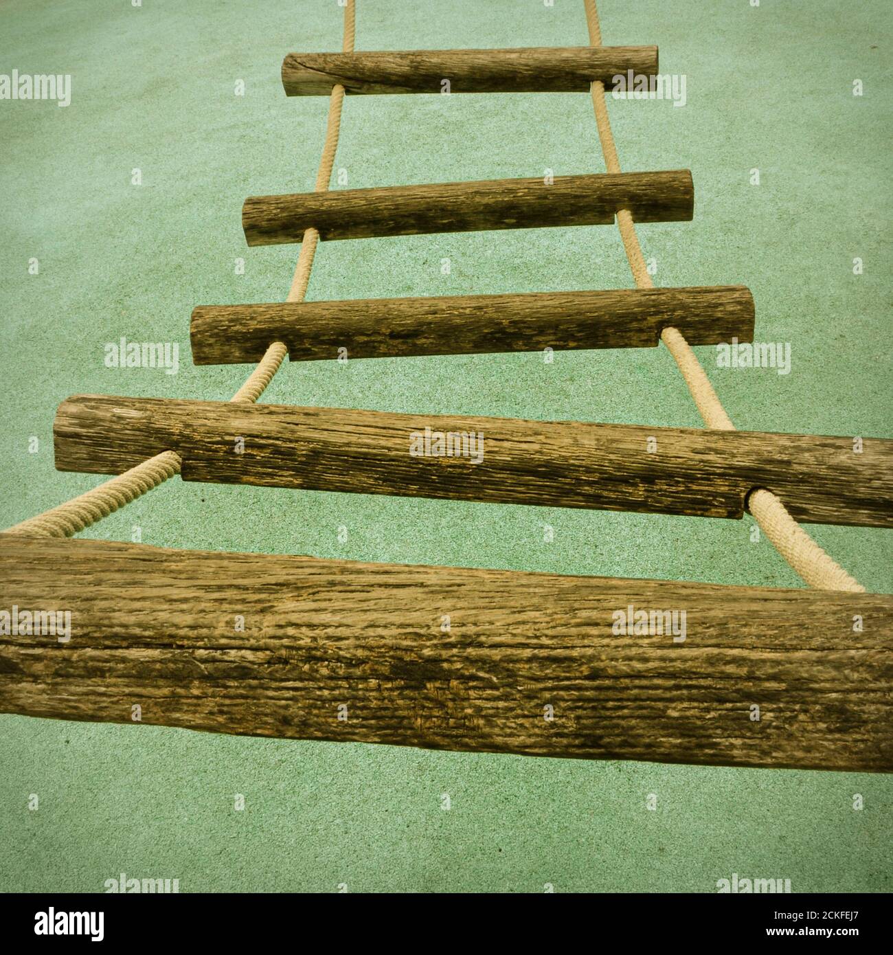 Una vista prospettica di una scala a corda con pioli in legno su un telaio per arrampicata per bambini. Foto Stock