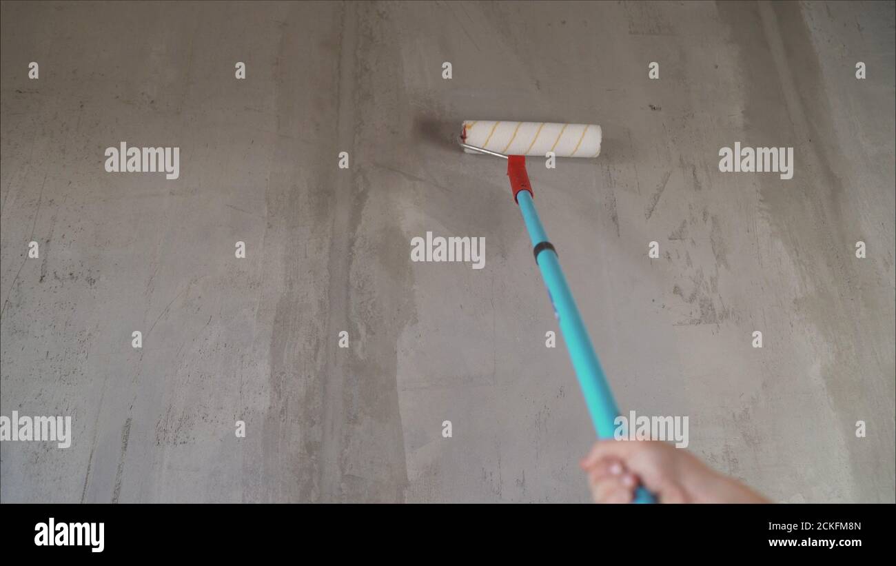 Un operaio inneschi le pareti con una spazzola. Verniciatura delle pareti con vernice di fondo con un pennello grande Foto Stock