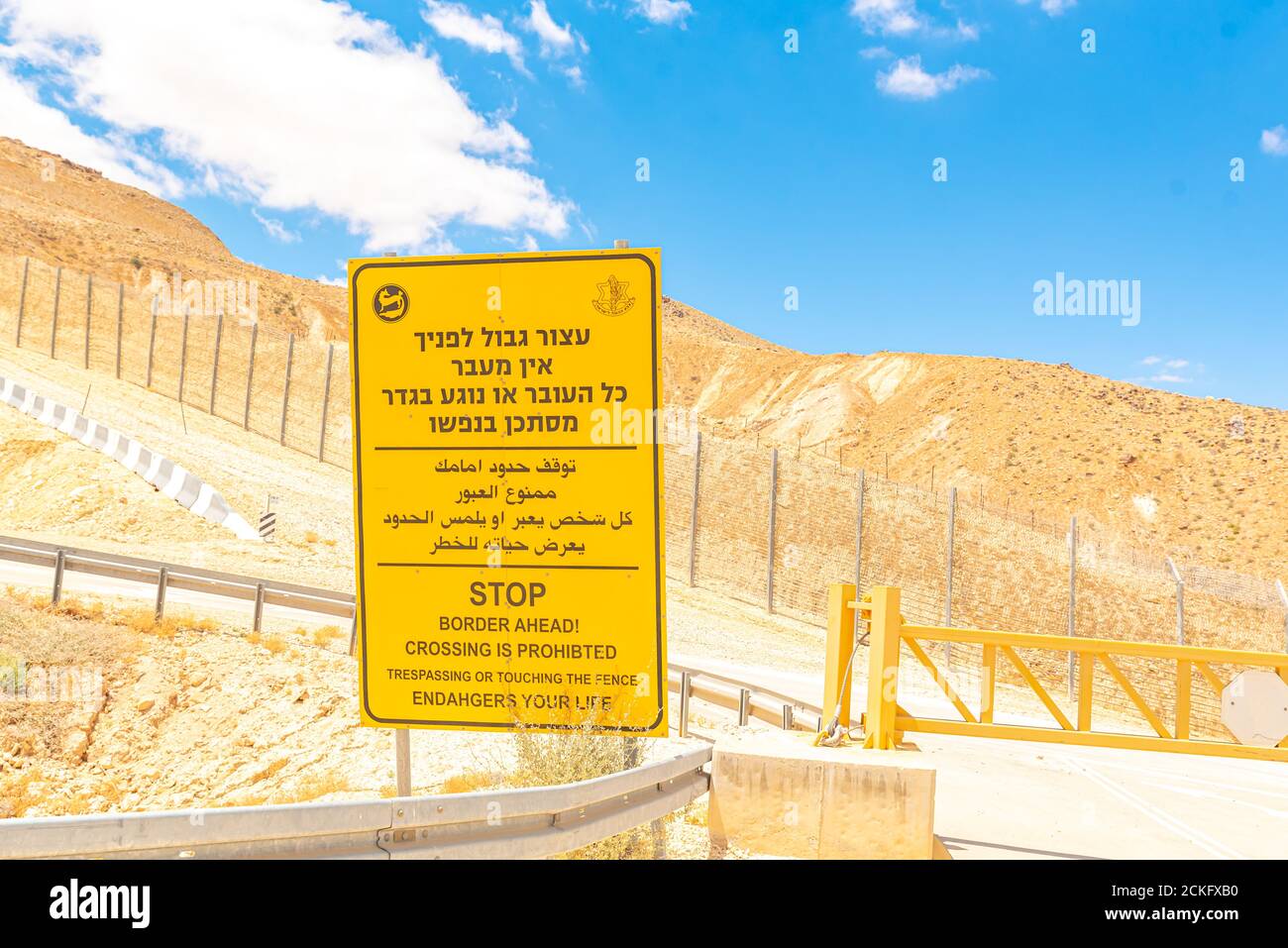 Percorso 10 lungo il confine egiziano - israeliano. Guardando in Egitto da Israele Yellow Boarder avanti cartello di avvertimento in ebraico arabo e inglese Foto Stock