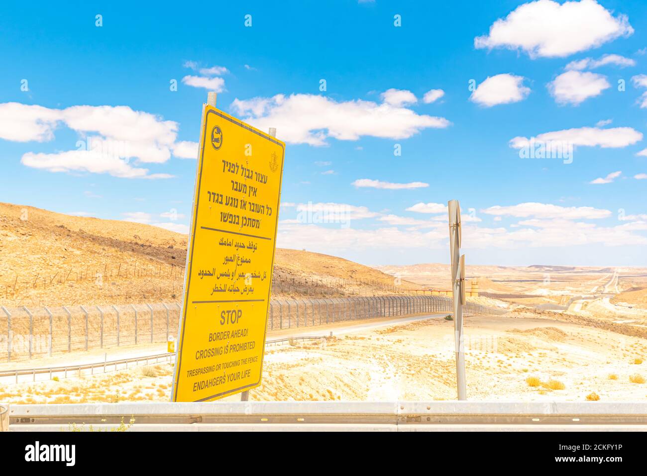 Percorso 10 lungo il confine egiziano - israeliano. Guardando in Egitto da Israele Yellow Boarder avanti cartello di avvertimento in ebraico arabo e inglese Foto Stock