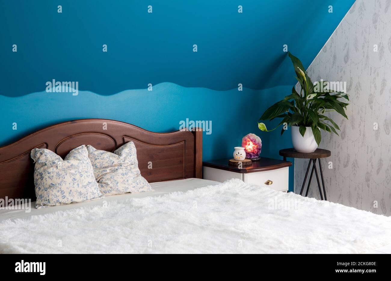 Camera da letto tranquilla di colore blu. Impianto di pulizia ad aria Spathiphyllum su supporto floreale, lampada di cristallo Amethyst illuminata e lampada aroma per rilassarsi Foto Stock