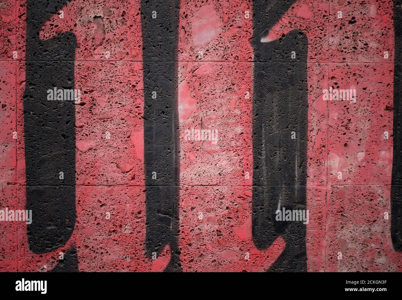 Un'immagine astratta della scritta Graffiti rossa su un buio Parete esterna Foto Stock