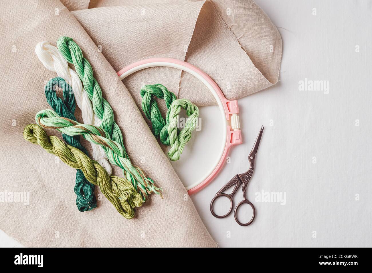 Set per ricamo. Tessuto di lino, motivi per ricamo, cerchio, filo verde e aghi. Spazio di copia, vista dall'alto Foto Stock