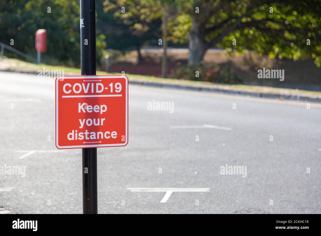Un segno che legge Coviid-19 mantenga la vostra distanza fissata ad a lampione Foto Stock
