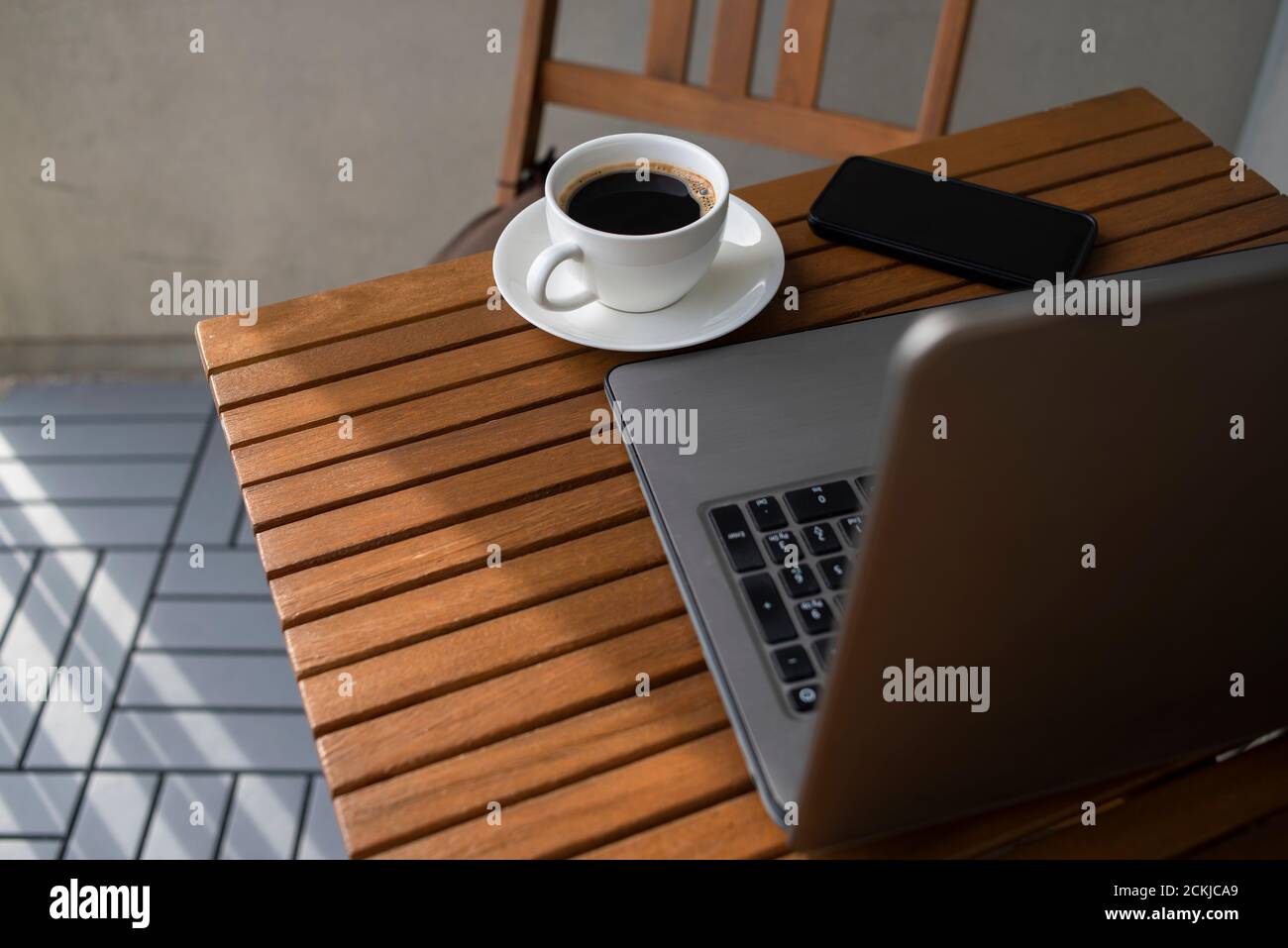 Ancora vita per lavorare in un caffè di strada con computer portatile. Tazza di caffè su un tavolo di legno. Foto Stock