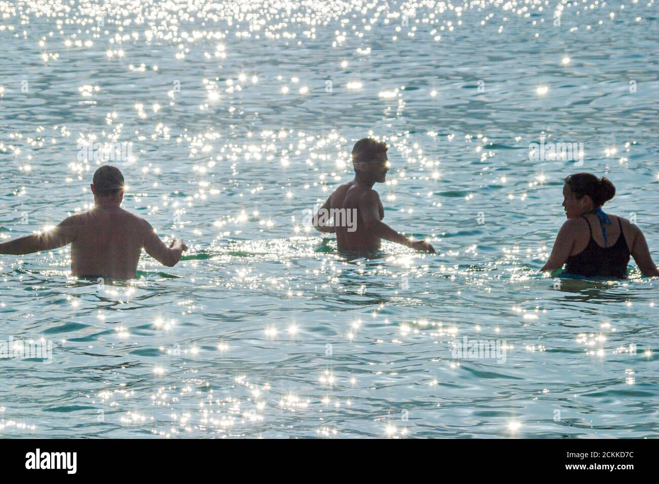 Miami Beach Florida,Atlantic Ocean Water pubblica spiaggia, silhouetted adulti wading nuoto uomo uomini donna oceano, visitatori turisti vacanza gruppo persone Foto Stock