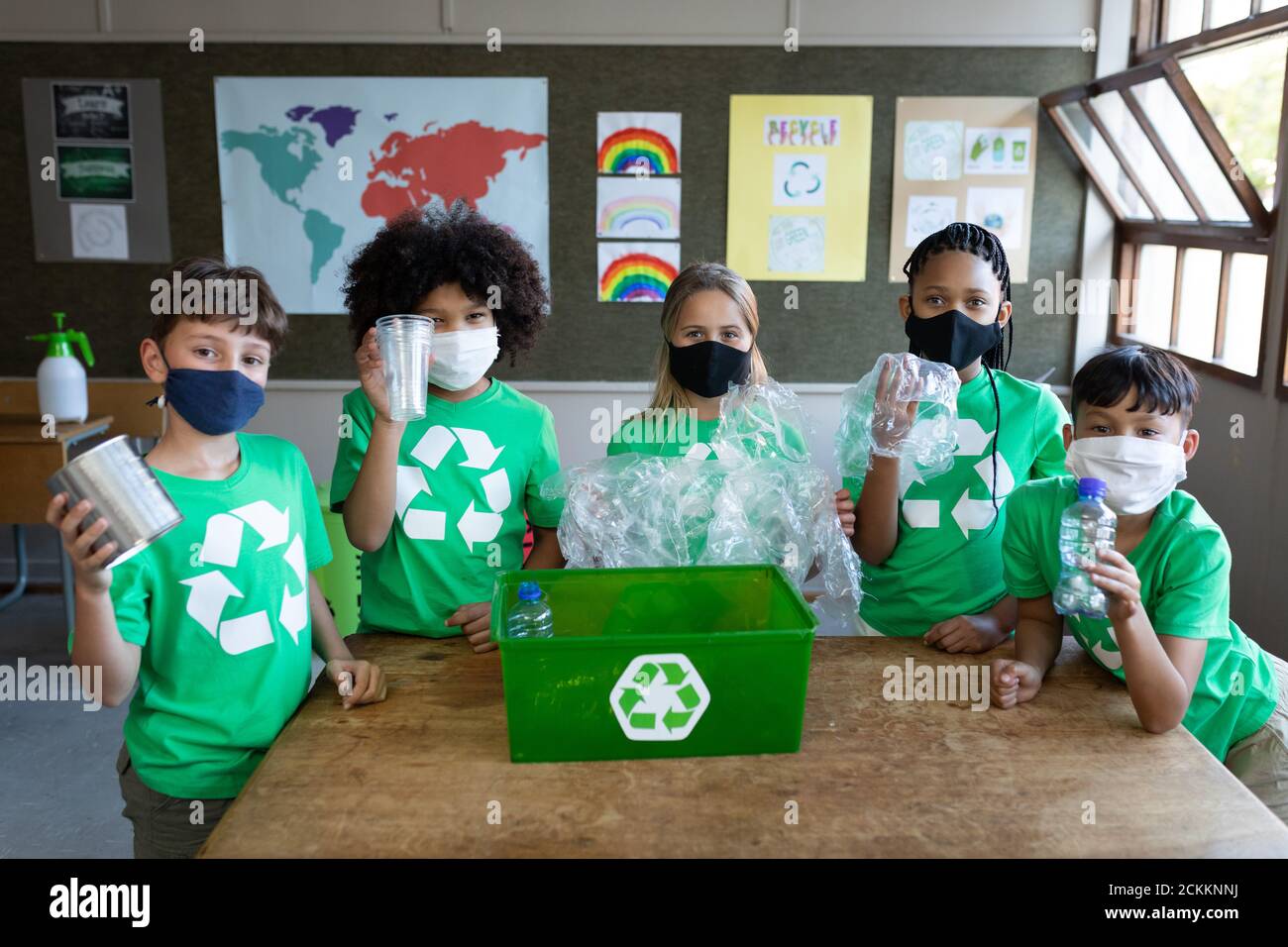 Ritratto di un gruppo di bambini che indossano maschere per il viso in plastica articoli in classe a scuola Foto Stock
