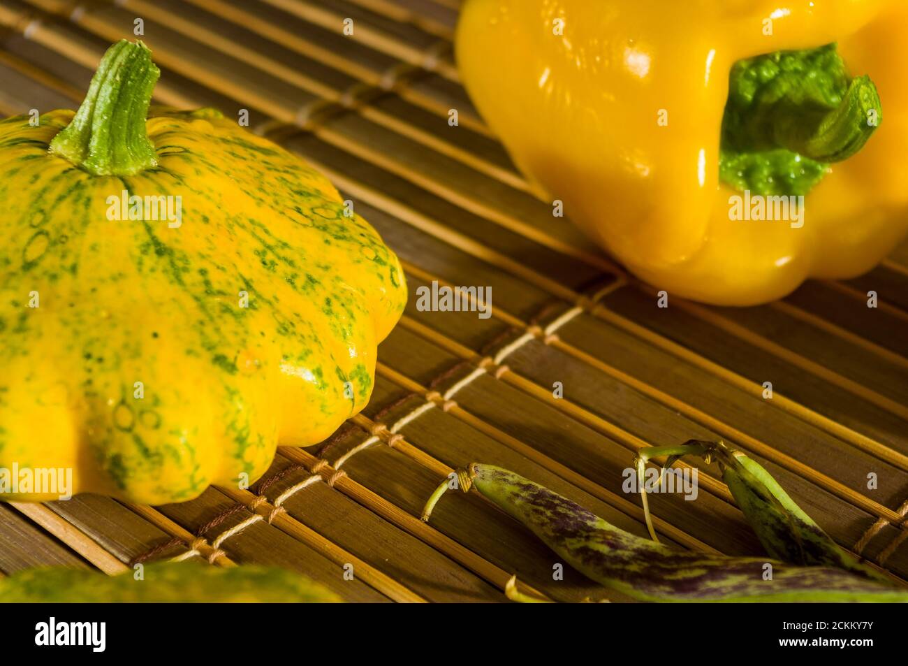 Autunno ancora vita - piccoli squash macchiato, fagioli asparagi, basilico viola, paprika su mat di bambù Foto Stock