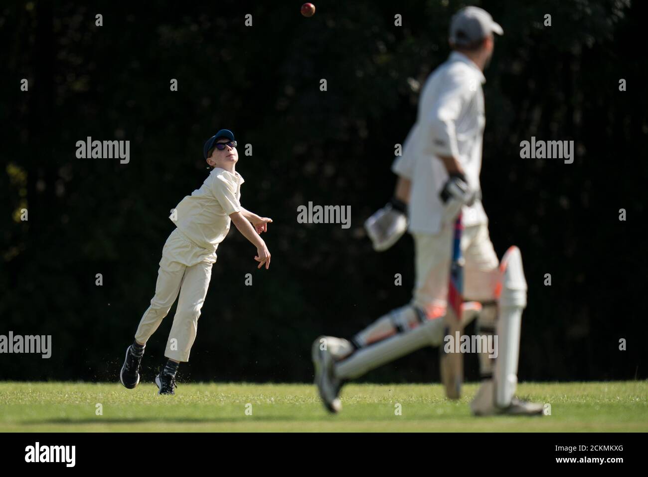 Giovane ragazzo che lancia la palla di cricket durante la partita di cricket villaggio per tutte le età. Foto Stock