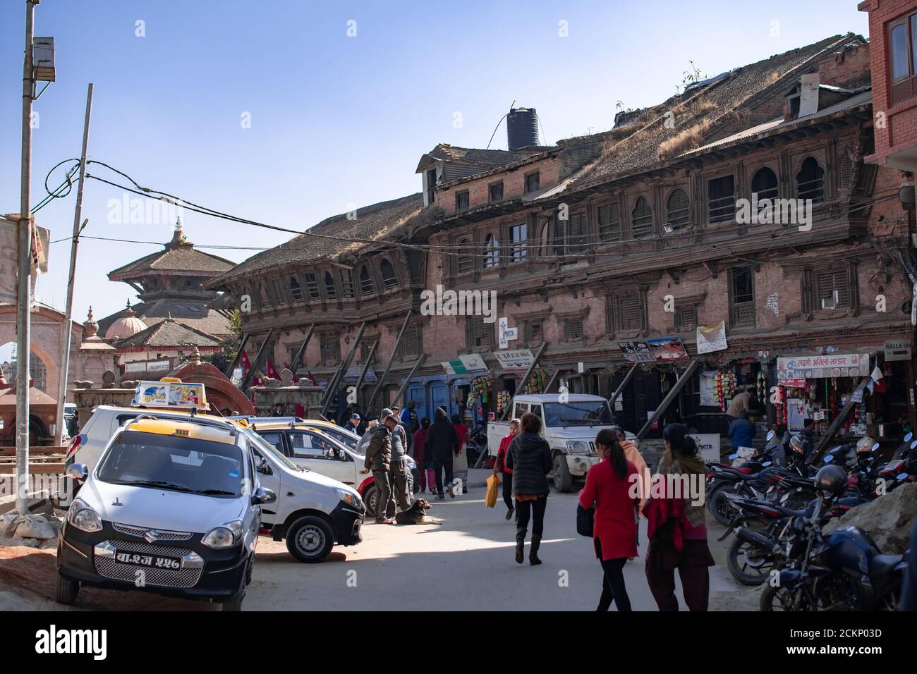 Bhaktapur, Kathmandu, Nepal - 23 dicembre 2019: Persone non identificate camminano per strada, moto e auto sono parcheggiate sul lato accanto ai negozi Foto Stock