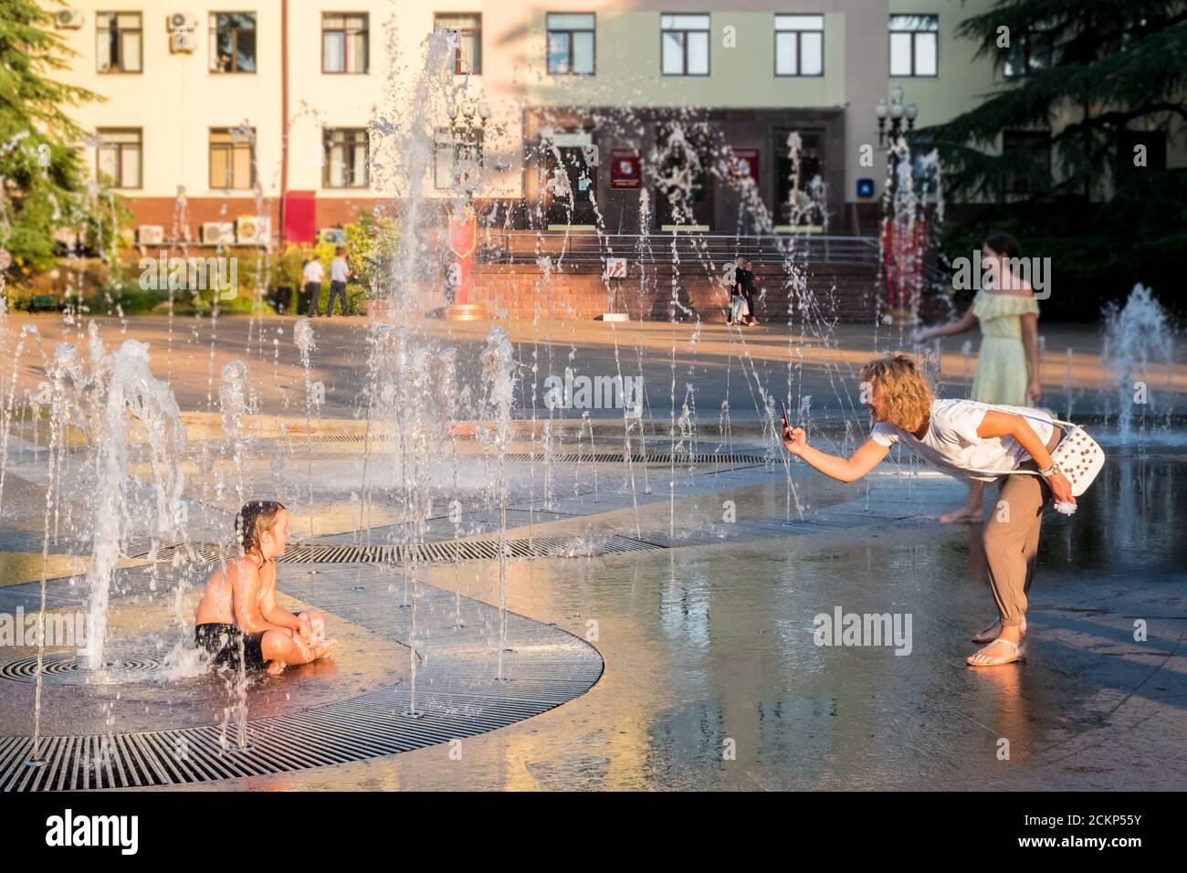 Sochi, Russia - 3 settembre 2020: Il bambino gioca nella fontana della città e posa per la mamma per una foto. Foto Stock