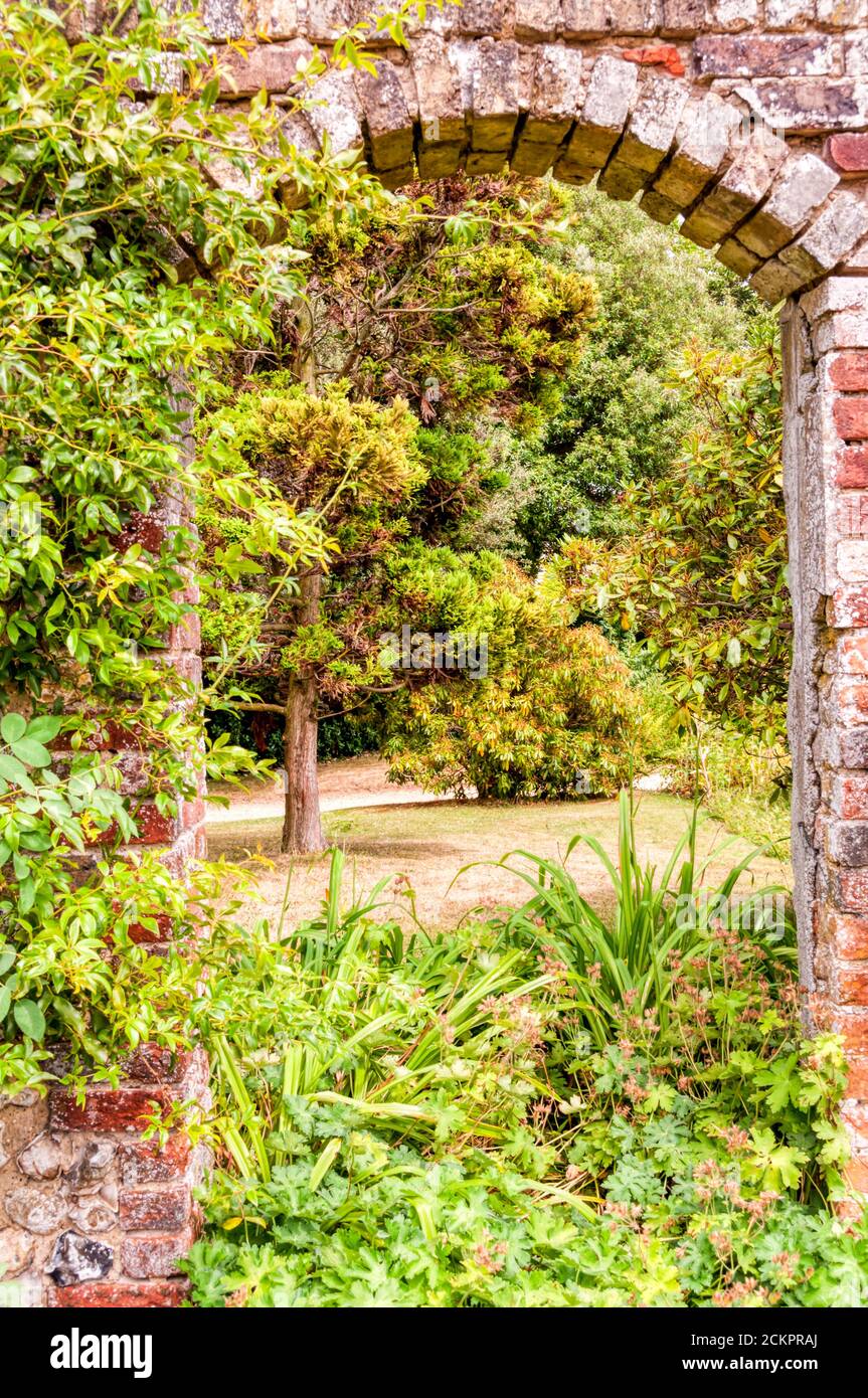 Vista attraverso un arco in un muro di mattoni nei giardini di Down House, Kent. Foto Stock
