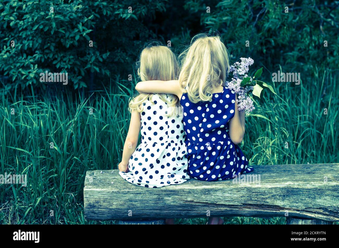 due ragazze bionde che siedono sulla vista posteriore della panca Foto Stock