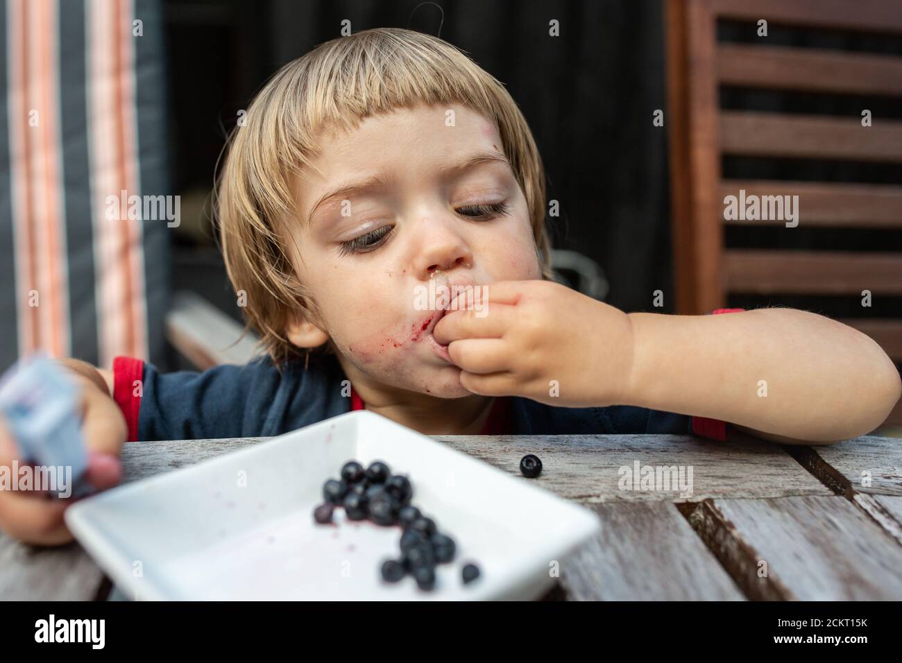 Ragazzo giovane che mangia mirtilli Foto Stock