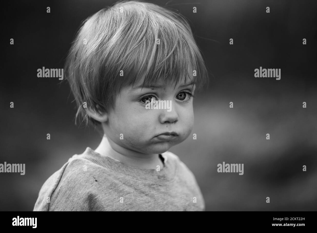 Primo piano di un ragazzo di due anni che ha un aspetto triste, B&W. Foto Stock