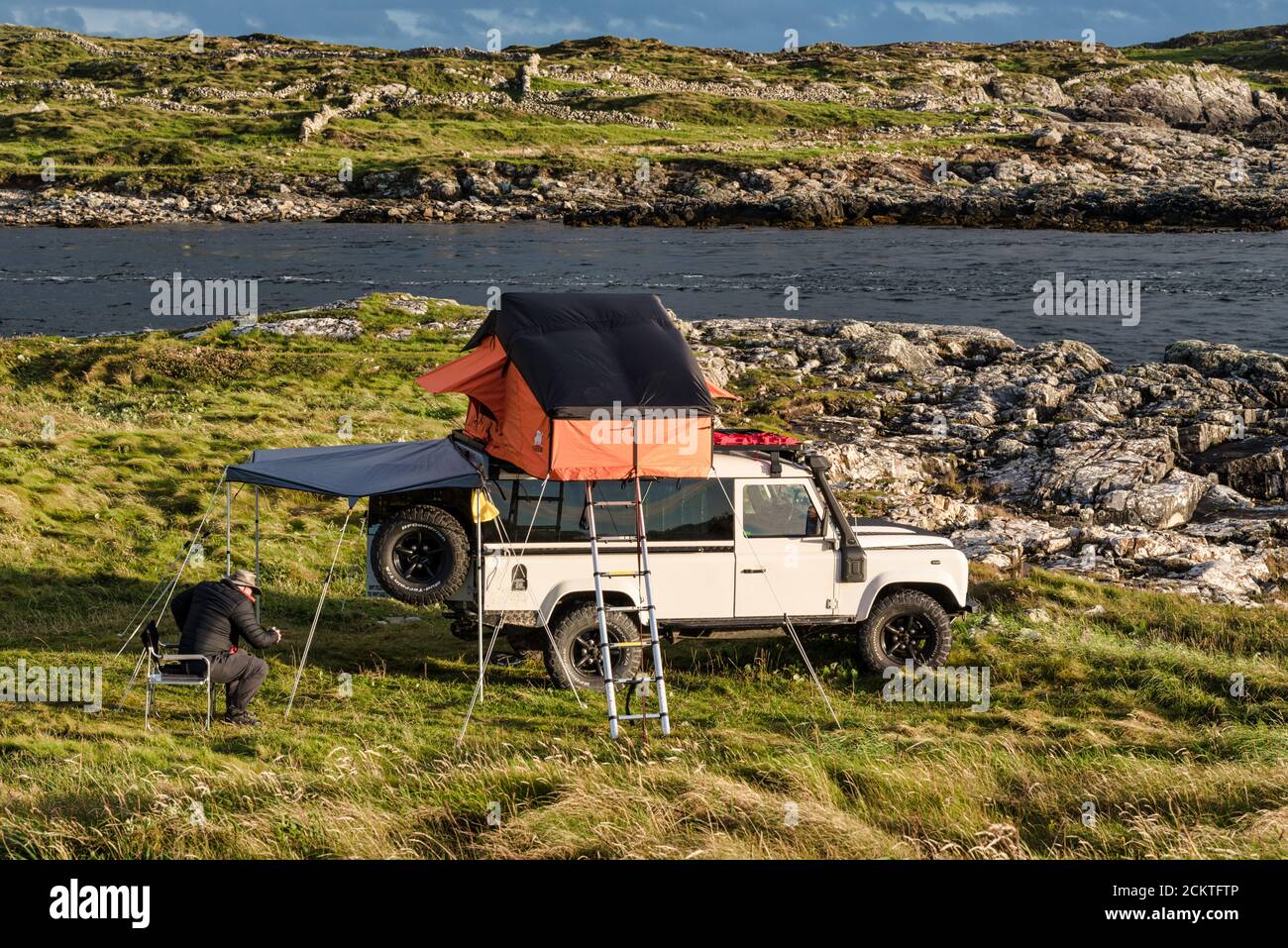 Clifden, Irlanda - 25 luglio 2020; un uomo che si accampano sulla costa occidentale dell'Irlanda in una Land Rover con una tenda sul tetto Foto Stock