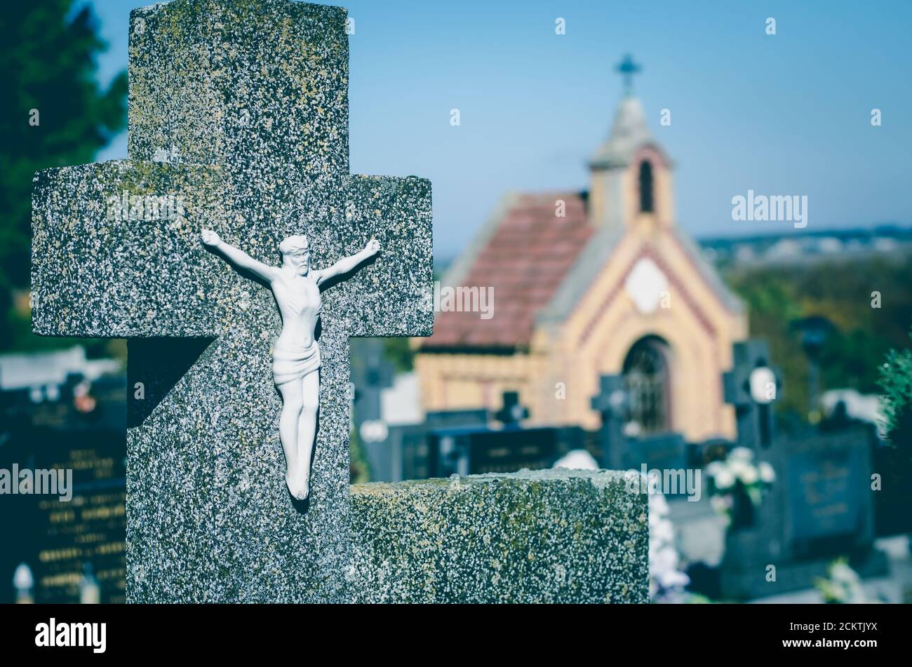 concetto religioso nel cimitero con croce simbolo e chiesa sullo sfondo Foto Stock