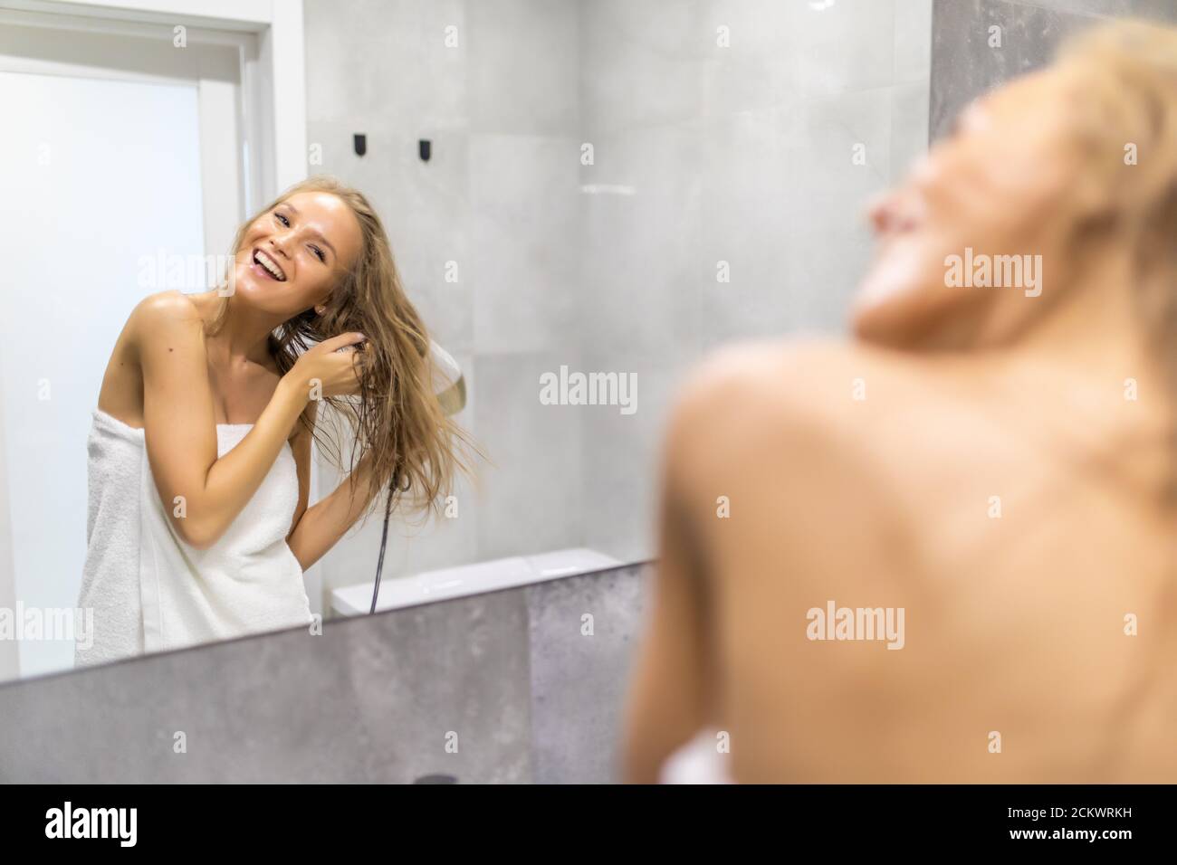 Felice giovane donna blow asciugacapelli nella stanza da bagno Foto Stock