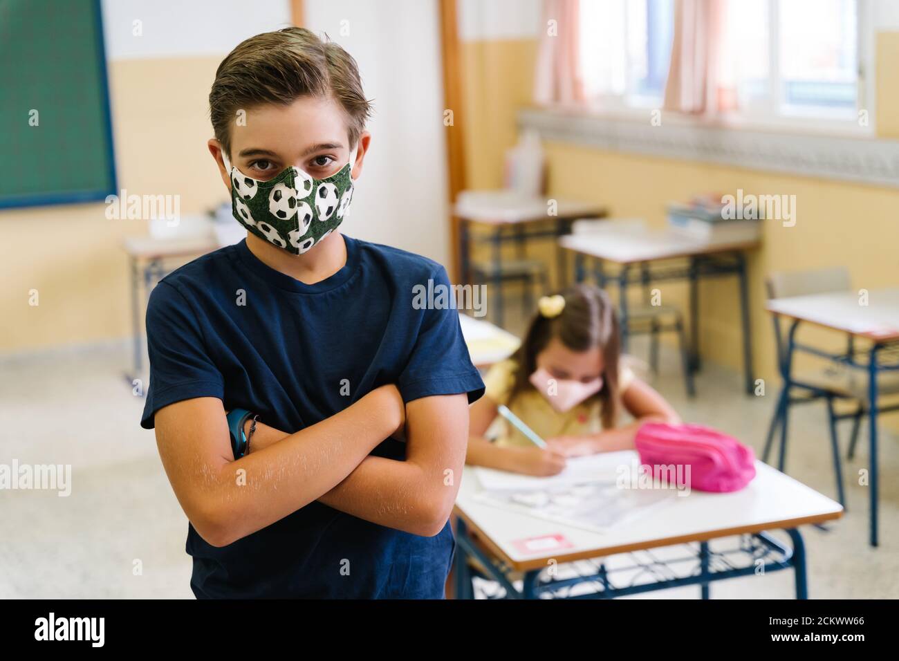 ragazzo studente che guarda la macchina fotografica in classe indossando una maschera. durante la pandemia covid Foto Stock
