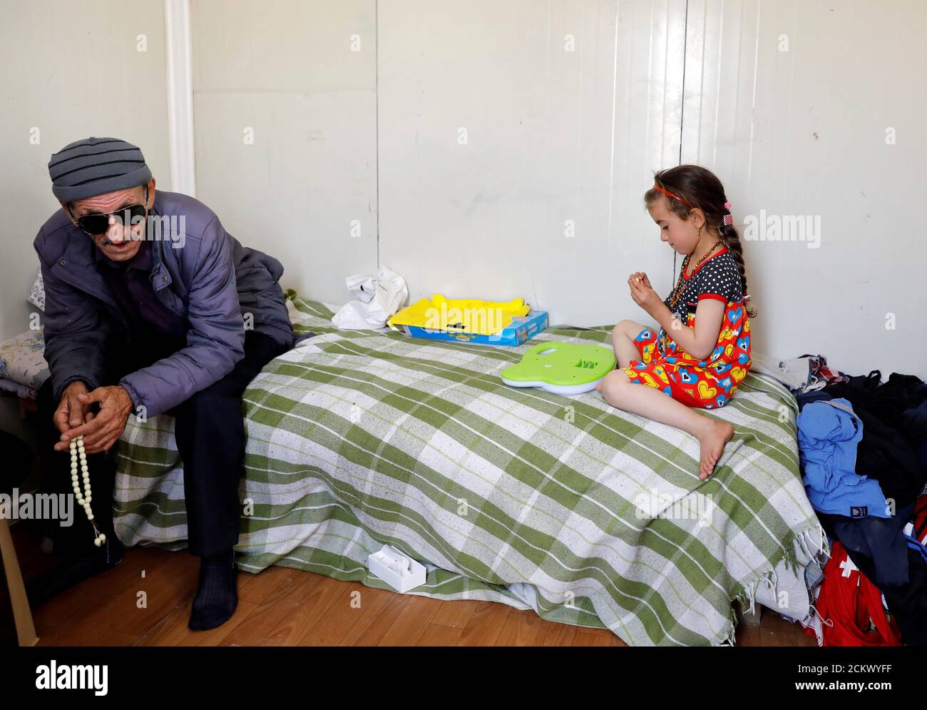 Christina Ezzo Abada irachena, ex ostaggio di militanti dello Stato islamico per tre anni, gioca vicino al padre cieco dopo essersi riunita con la sua famiglia in una casa ristretta in un campo profughi a Erbil, Iraq, 10 giugno 2017. REUTERS/Erik De Castro Foto Stock