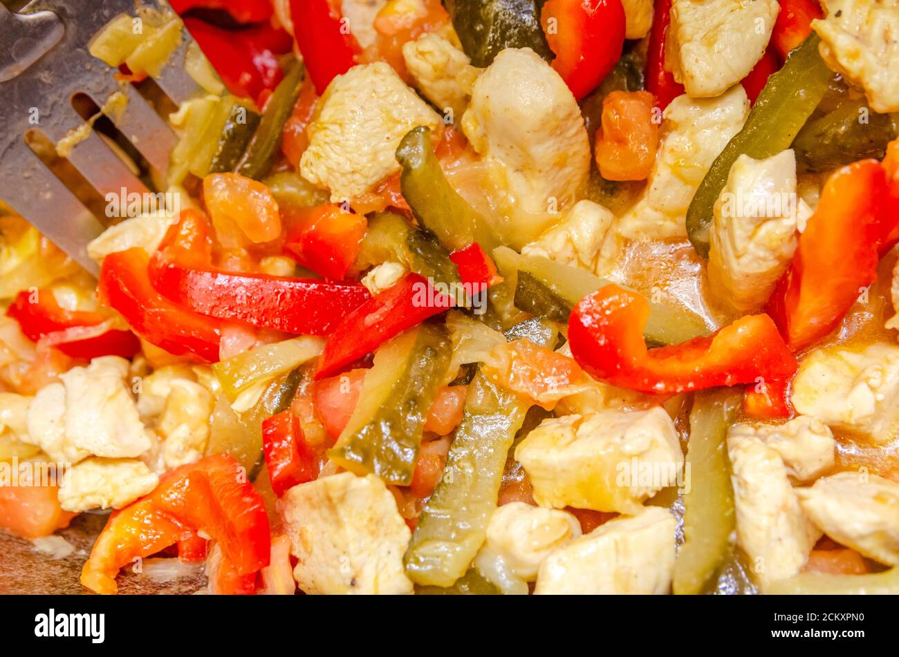 Nel calderone fritti pezzi di carne di pollo, peperoni rossi, pomodori, sottaceti, cipolle bianche Foto Stock