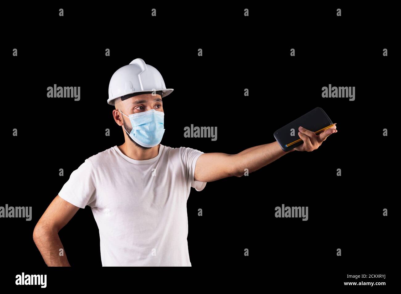 Giovane uomo ispanico di costruzione con maschera che stima una misura Foto Stock