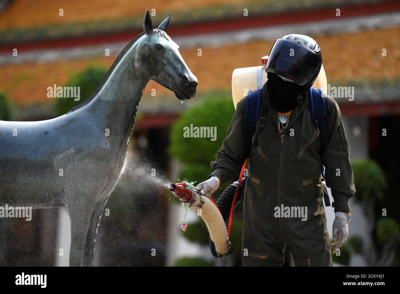 Un operatore sanitario spruzzi disinfettante a causa dell'epidemia di coronavirus all'interno del tempio di Wat Suthat Thepwararam a Bangkok, Thailandia 17 marzo 2020. REUTERS/Chalinee Thirasupa Foto Stock