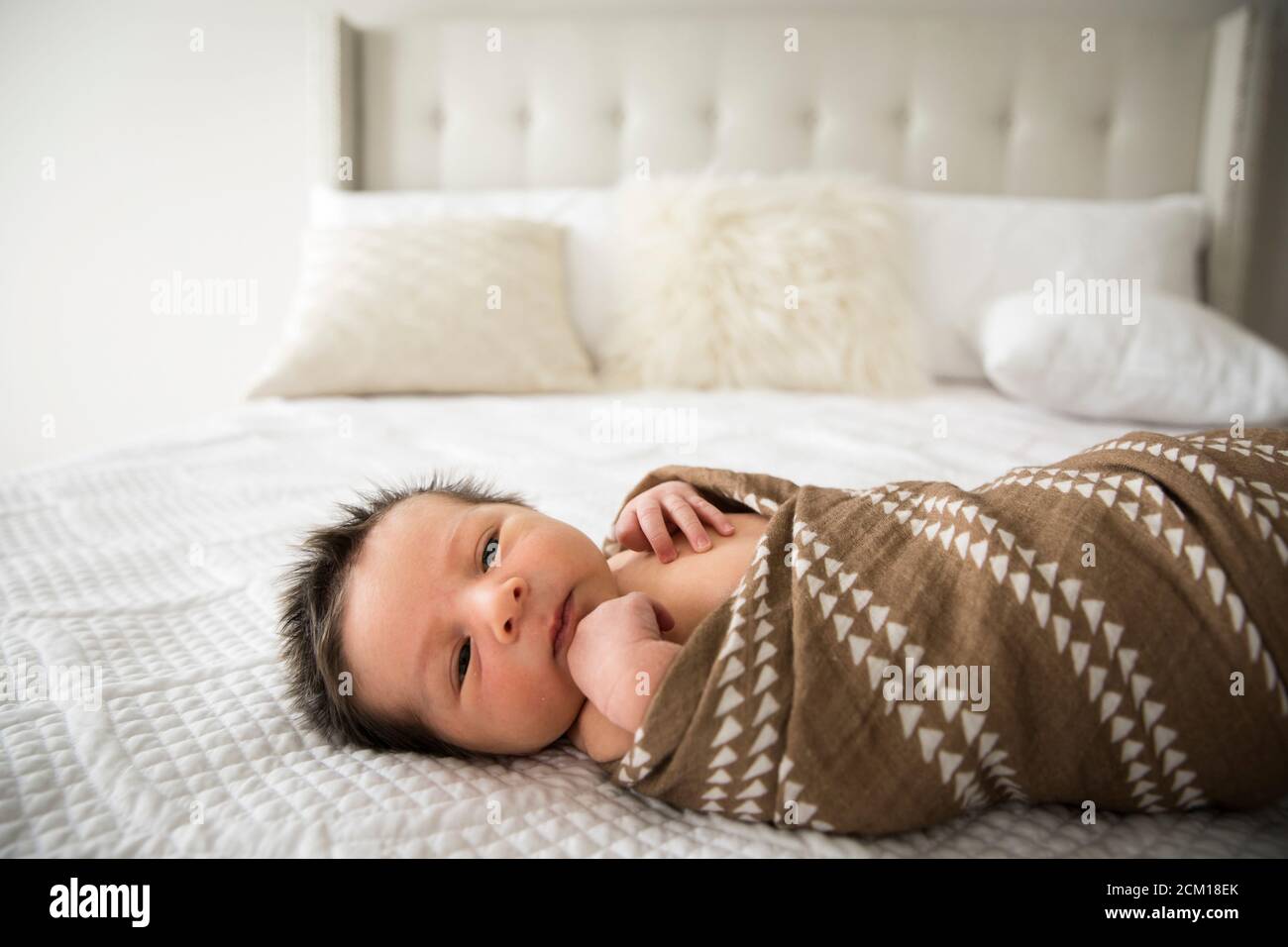 Neonato Baby con un sacco di capelli scuri si è addondato su Letto a casa Foto Stock