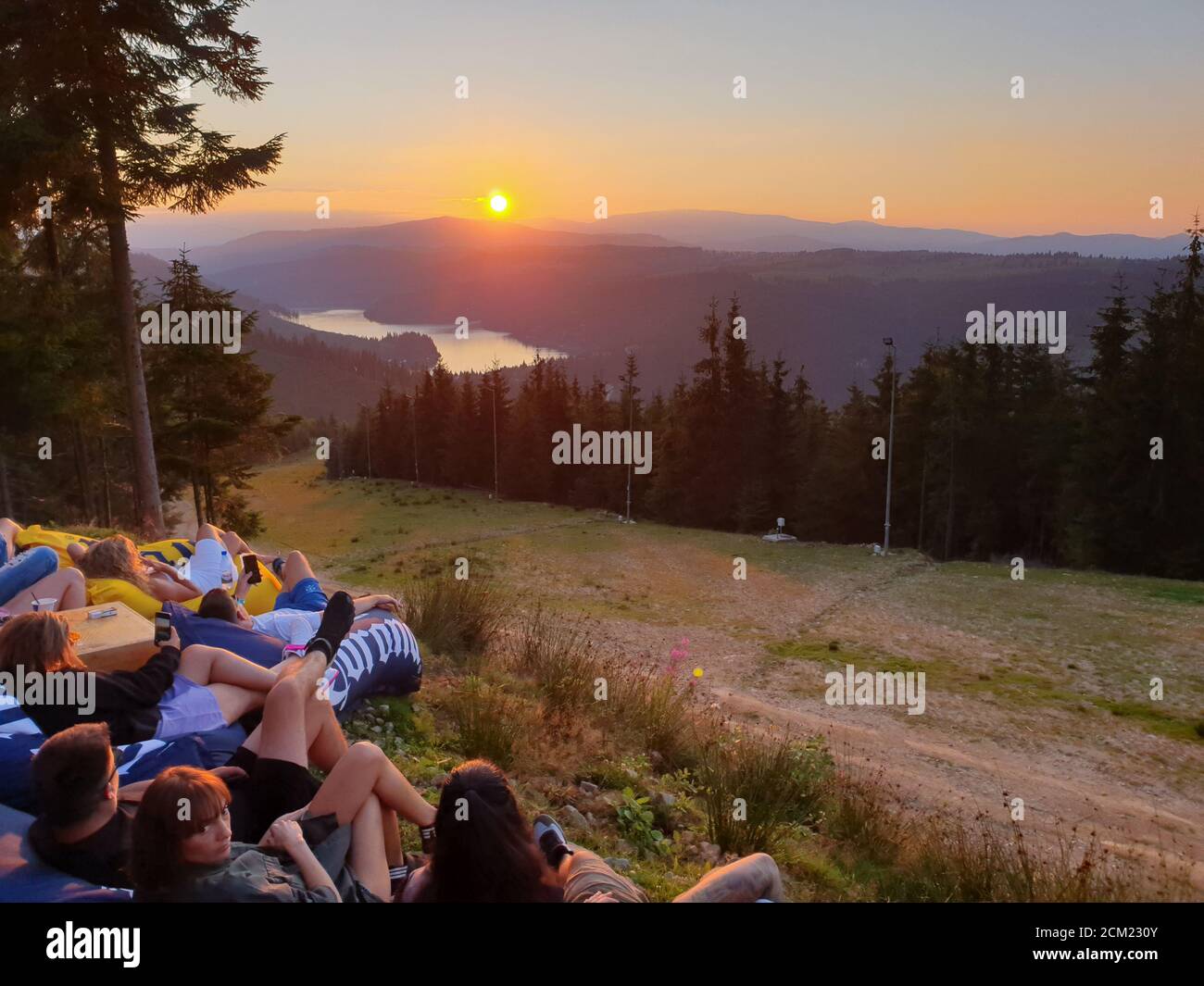 I giovani si rilassano, guardando il tramonto in montagna, sul lago Belis, a Marisel, Cluj contea, Transilvania, Romania. Attività all'aperto nella natura w Foto Stock