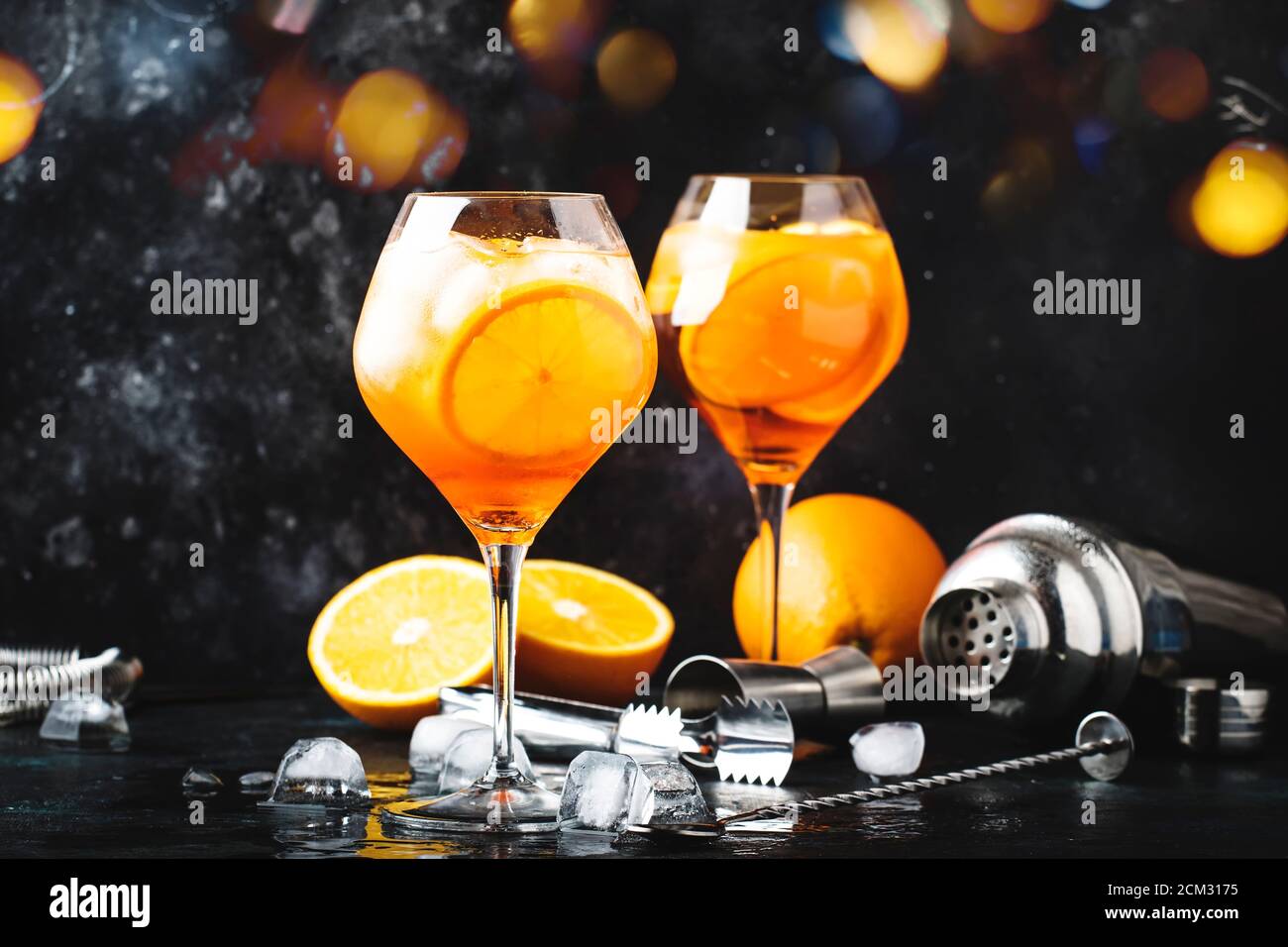 Cocktail Aperol Spritz in grande bicchiere di vino con arancia e ghiaccio, bevanda alcolica estiva, banco bar scuro con utensili da bar in acciaio, spazio copia Foto Stock