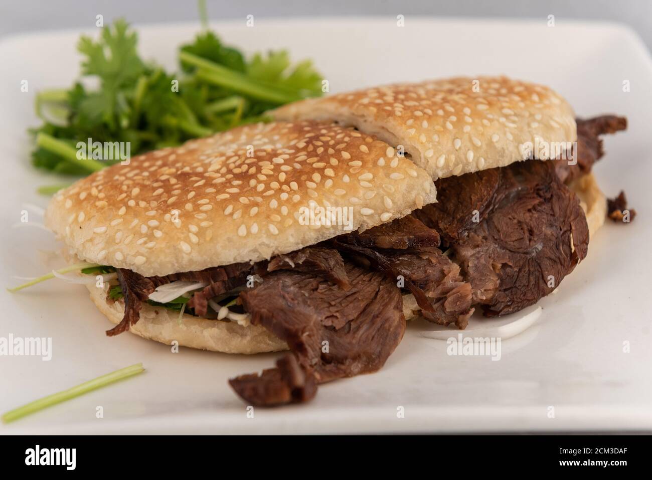 Vista dettagliata su un piatto appetitoso che alletta le papille gustative con sandwich di manzo in panino di sesamo di dimensioni perfette. Foto Stock