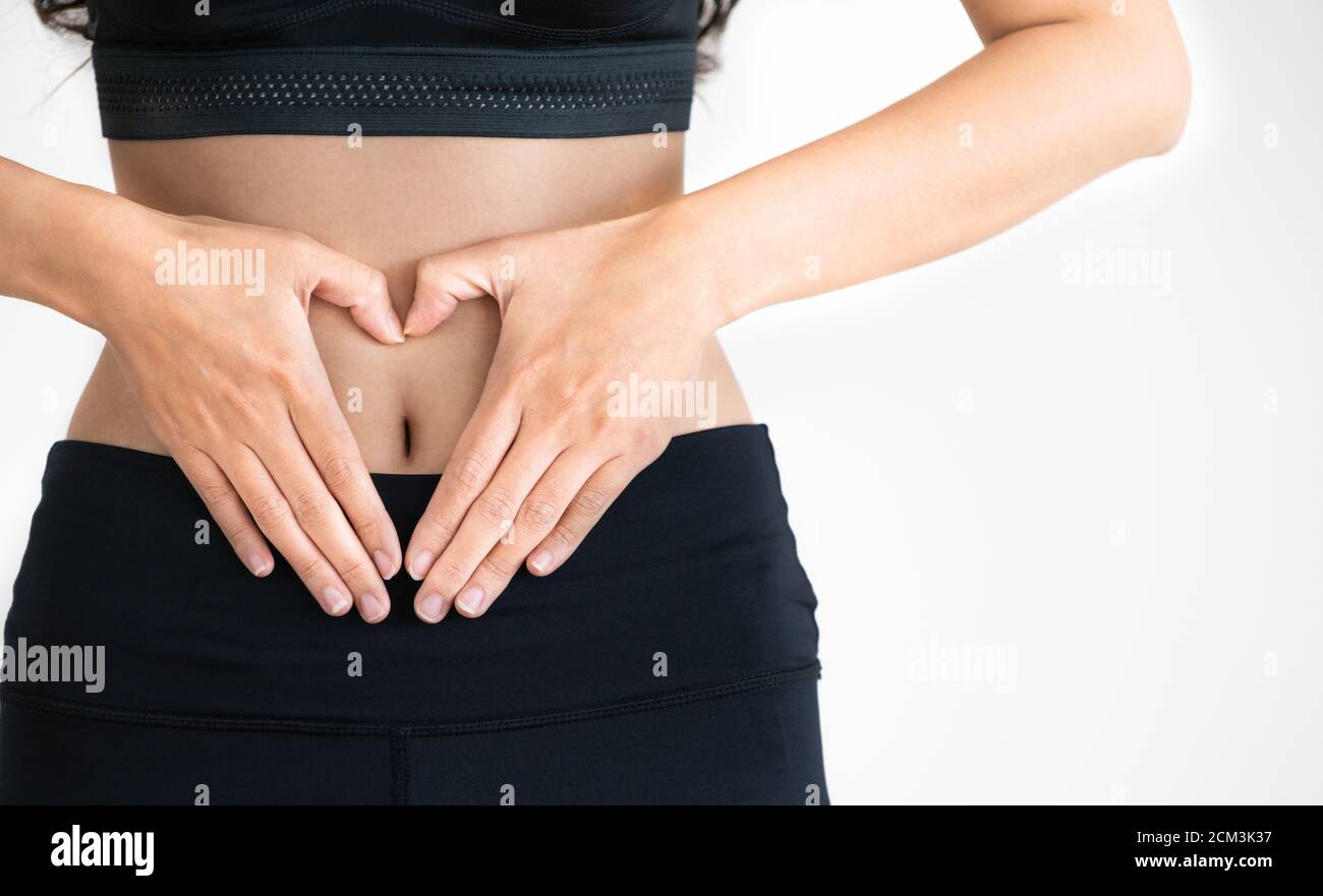Immagine ravvicinata di giovane donna in sportswear messa a forma di cuore gesto a suo addome. Dieta perdita di peso e di nutrizione sana nozione. Foto Stock
