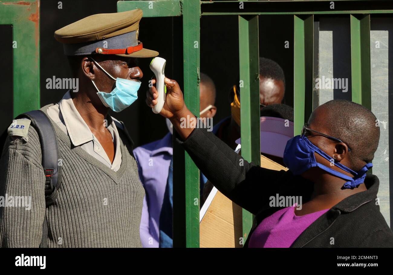 Una persona controlla la temperatura di un poliziotto durante un blocco a livello nazionale per contribuire a frenare la diffusione della malattia del coronavirus (COVID-19) in Harare, Zimbabwe, 14 maggio 2020. REUTERS/Philimon Bulawayo Foto Stock