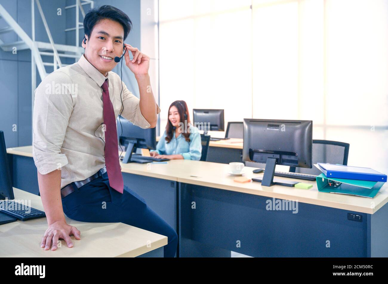 Giovane agente del servizio clienti uomo con cuffie e computer che lavorano in ufficio. Concetto di operatore professionale. Foto Stock