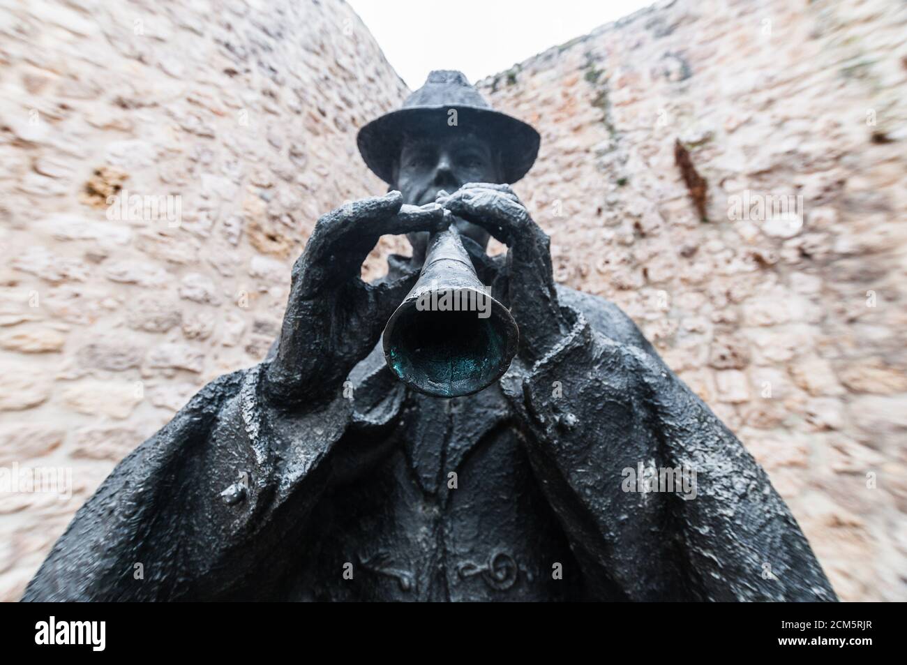 Statua in bronzo di un tradizionale musicista folk che suona un tipico strumento eolico chiamato 'Dulzaina' di fronte a un muro lapidato a Burgos, Spagna. Foto Stock