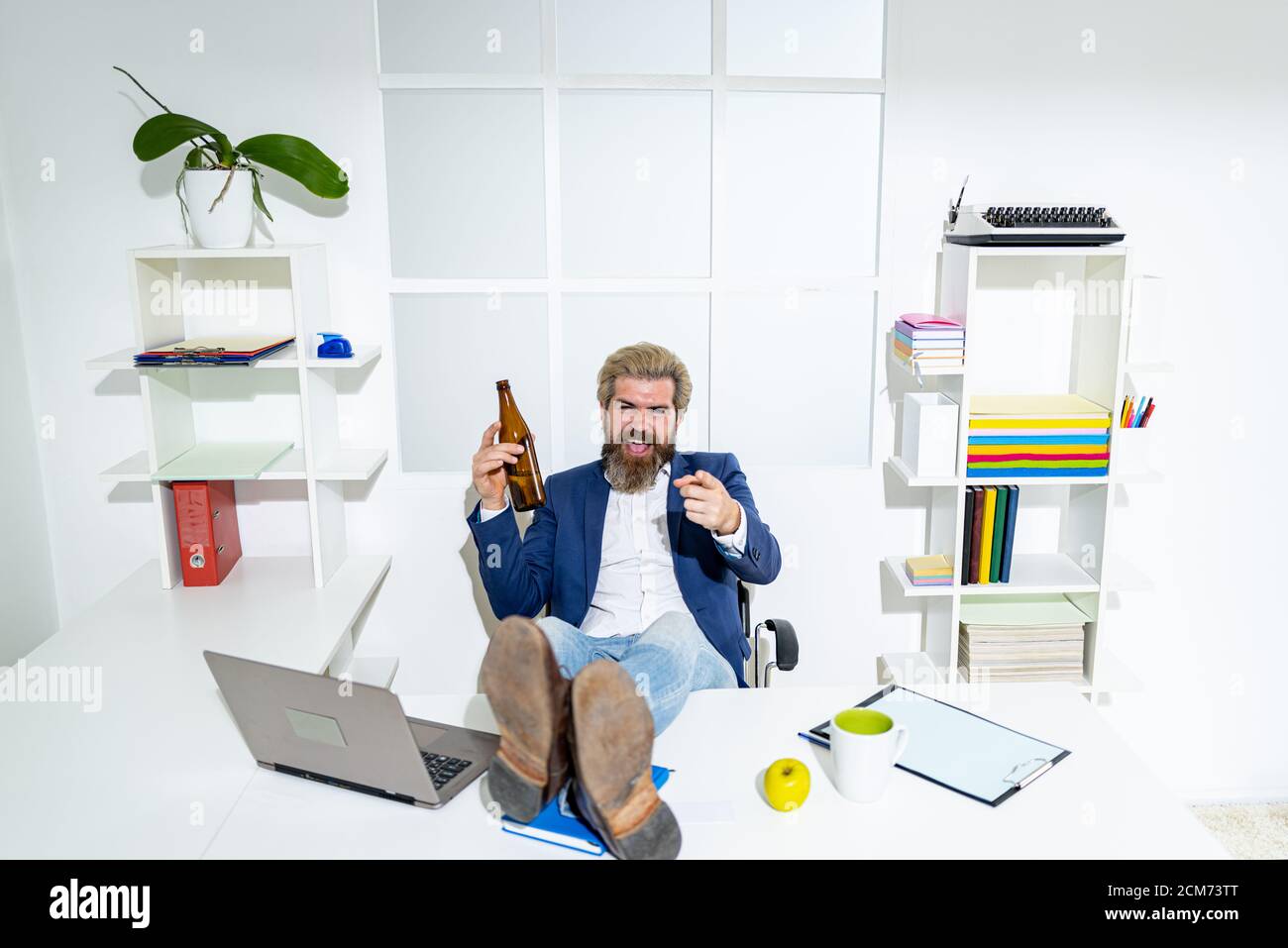 Uomo d'affari stanco annoiato che brilica sul posto di lavoro vicino al laptop, lavoro noioso, lavoro di fine lavoro morto, overwork extra dopo l'orario di lavoro, bere alcol. Lavoratore ubriaco in ufficio. Foto Stock