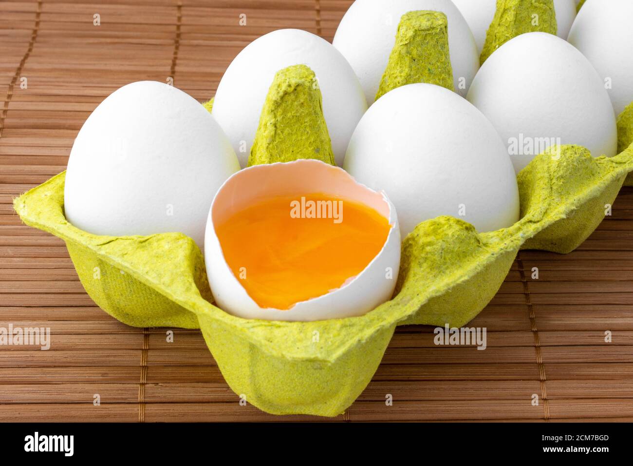 uova di pollo in un pacchetto, isolato su un tavolo di legno, un uovo è aperto, concetto di cibo Foto Stock