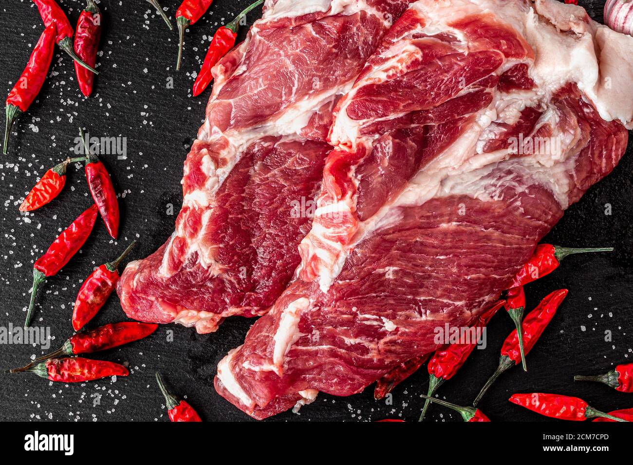 due pezzi di manzo marmorizzato fresco su fondo scuro, con spezie per cucinare la bistecca, orizzontale Foto Stock