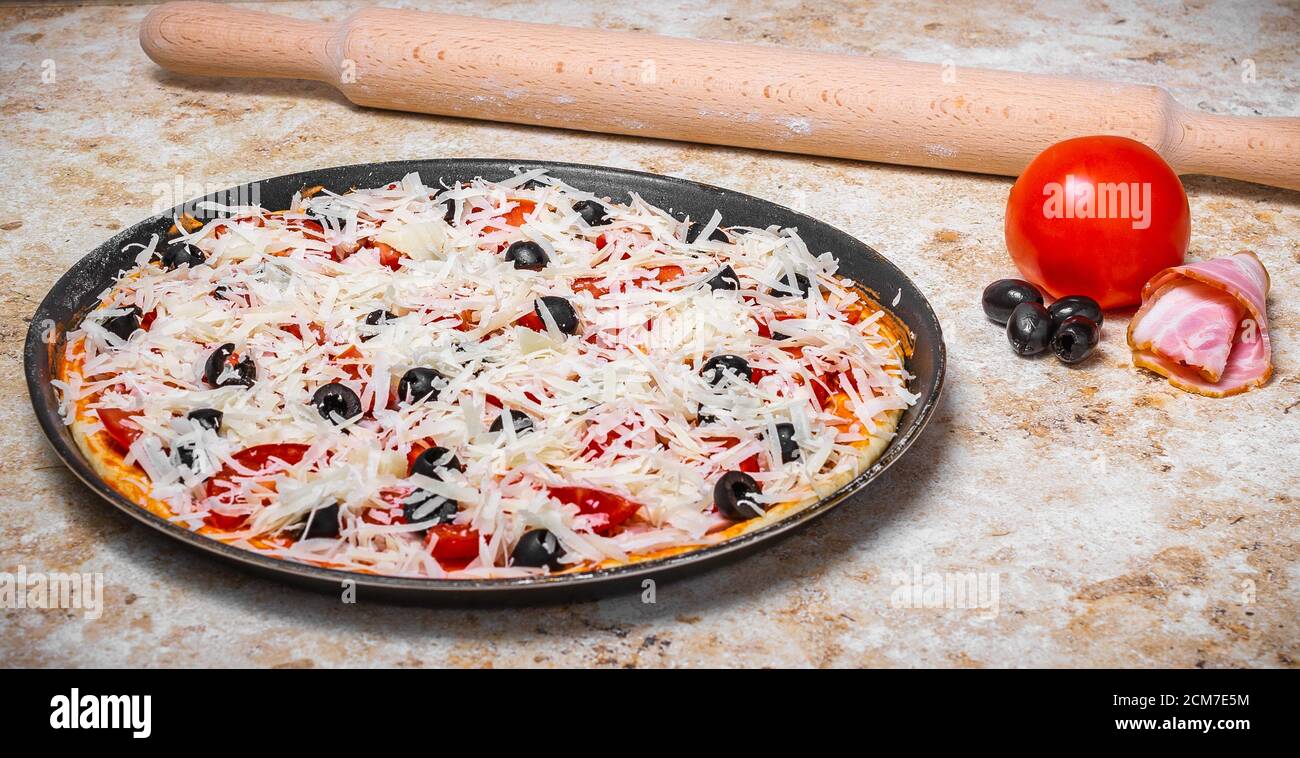 Preparare una pizza a casa con pomodoro e formaggio Foto Stock