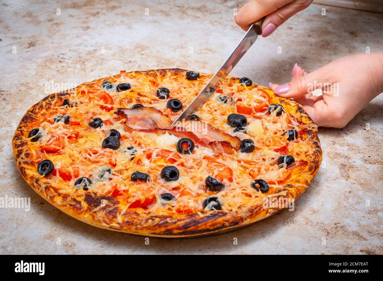 Fare una pizza a casa con pomodoro, olive, prosciutto e formaggio, Cook at home concept. Foto Stock