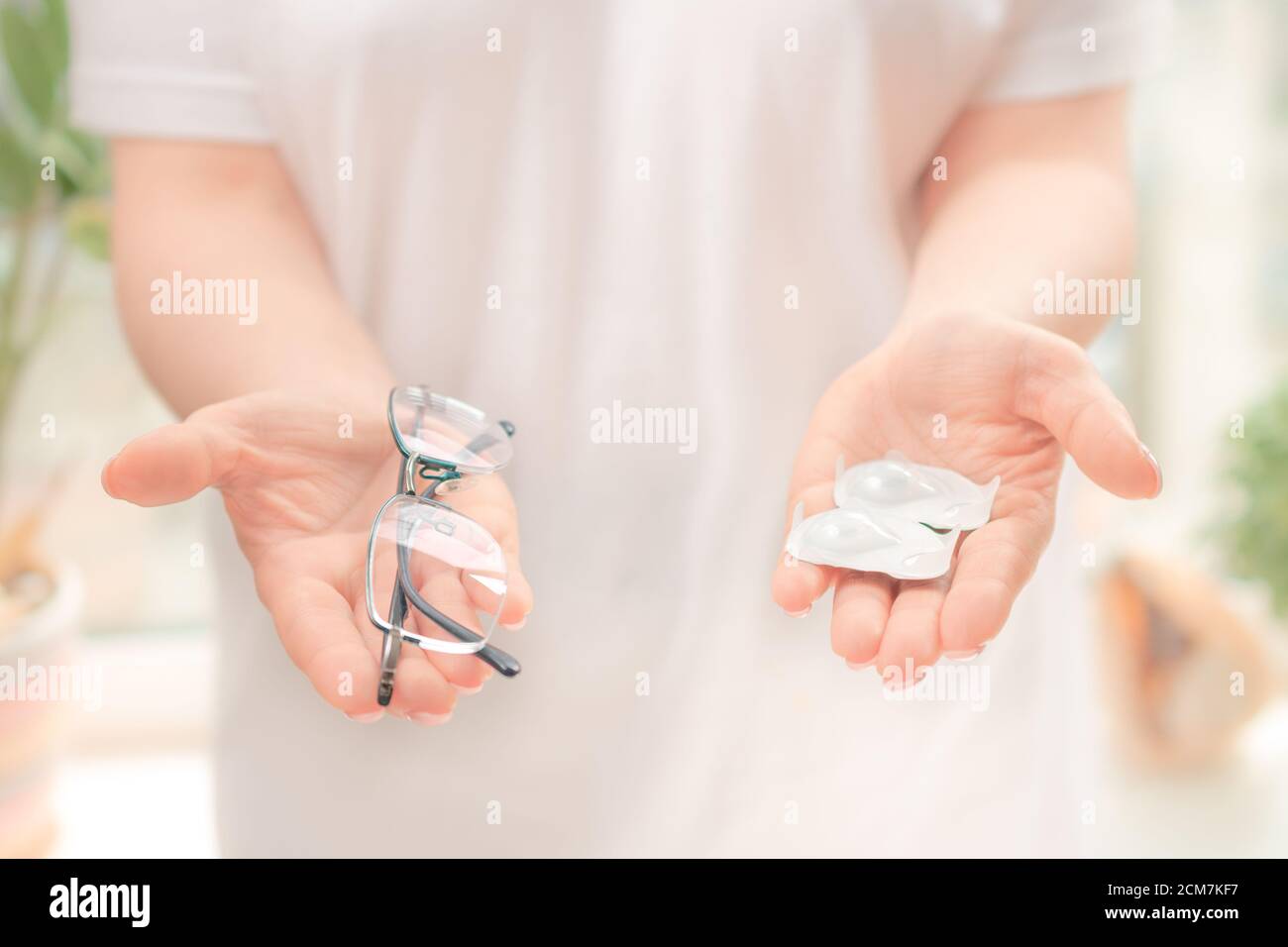 le mani della donna tengono il vaso di vetro con le monete all'interno, miopia e concetto di problema di vista. Foto Stock