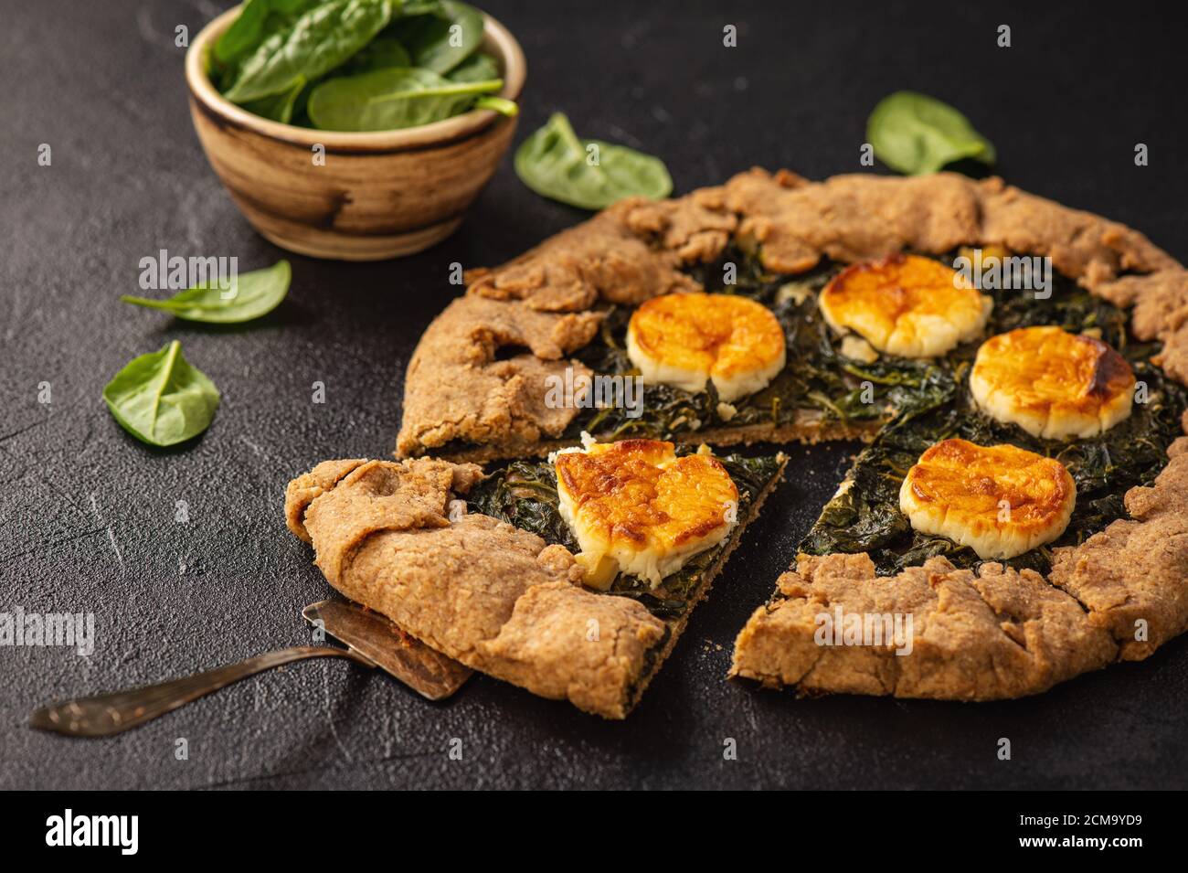 Galette rustiche di spinaci e formaggio di capra su sfondo nero. Foto Stock