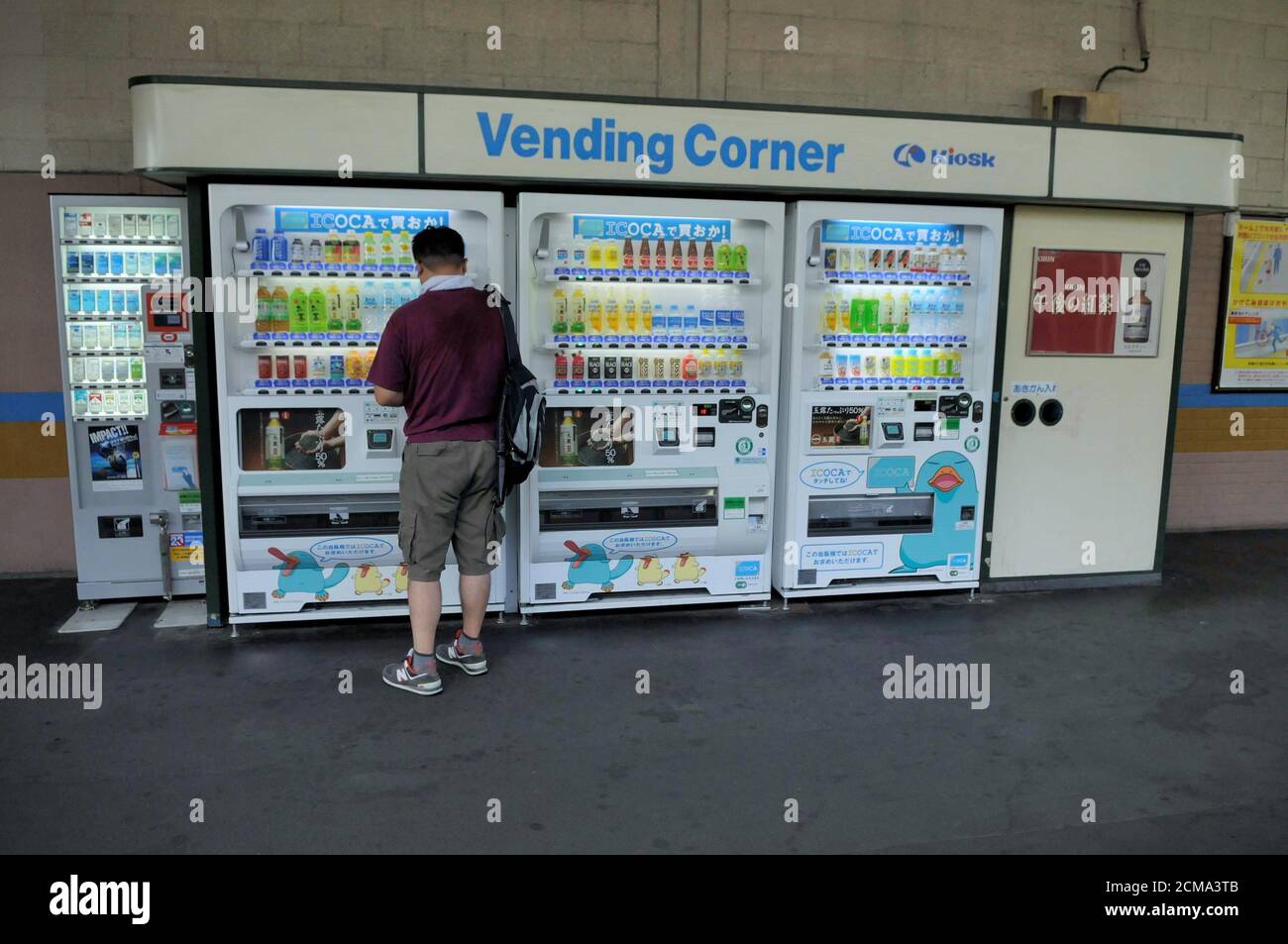 UNA PERSONA DAVANTI A UNA MACCHINA AUTOMATICA PER IL CALDO E BEVANDE FREDDE Foto Stock