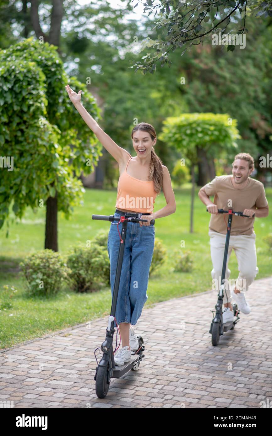 Giovane coppia in sella a uno scooter nel parco e sentirsi bene Foto Stock