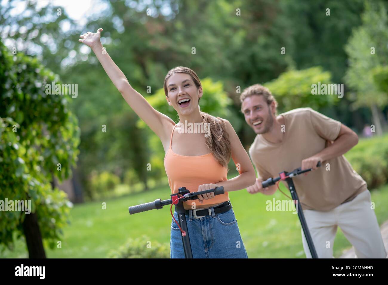 Una giovane coppia di scooter in sella al parco e che guarda entusiasta Foto Stock